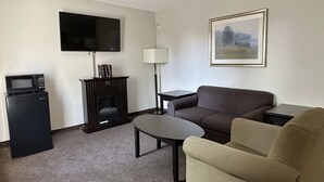 Ett vardagsrum med en platt-TV, en öppen spis, en soffa, ett soffbord och en lampa.