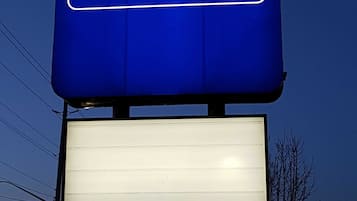 A Travelodge sign with a large illuminated blue signboard and a blank white sign below it.