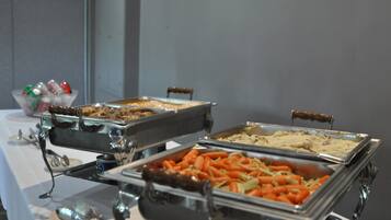 A buffet table with various food items in metal serving trays.