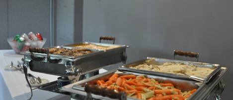 A buffet table with various food items in metal serving trays.