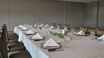 A long dining table set with white tablecloths, plates, glasses, and napkins.