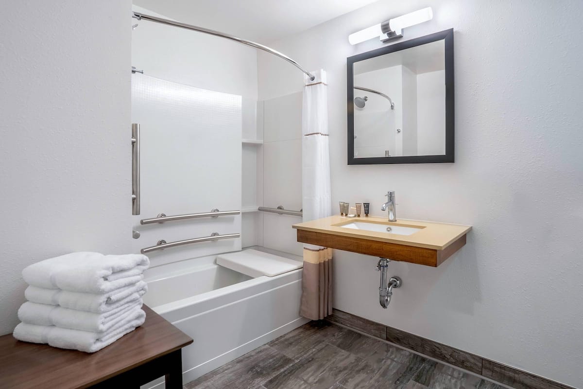 A modern bathroom with a shower, a sink, and a mirror.