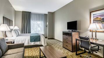 A hotel room with a bed, a desk, a chair, a television, and a window with curtains.