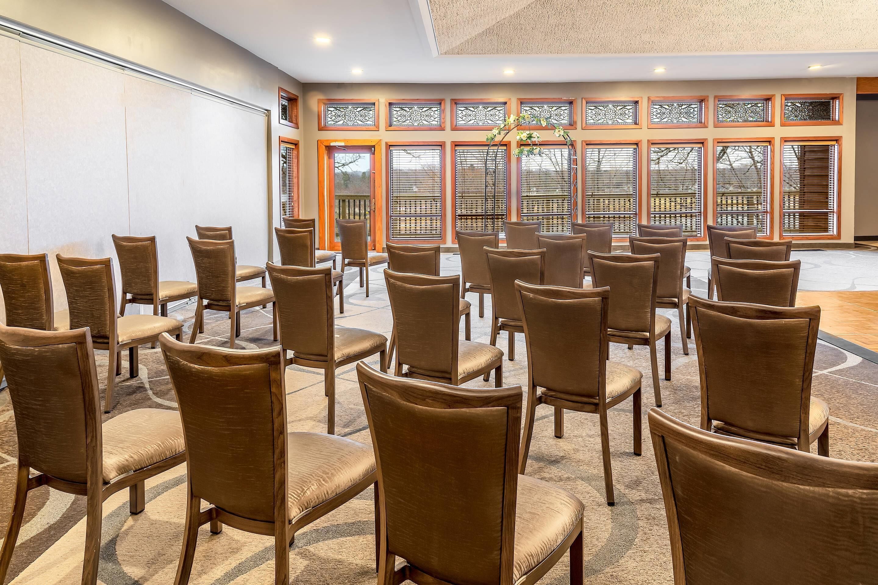 A conference room with rows of chairs and a large window with decorative glass panels.