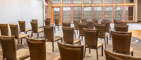 A conference room with rows of chairs and a large window with decorative glass panels.