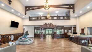 A spacious lobby with a wooden floor, a large chandelier, a reception desk, and a statue of a wolf. - Riverview Inn & Suites, an Ascend Collection Hotel (Rockford)