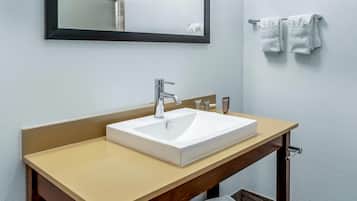 A bathroom with a white sink, a mirror, and two towels hanging on a rack.