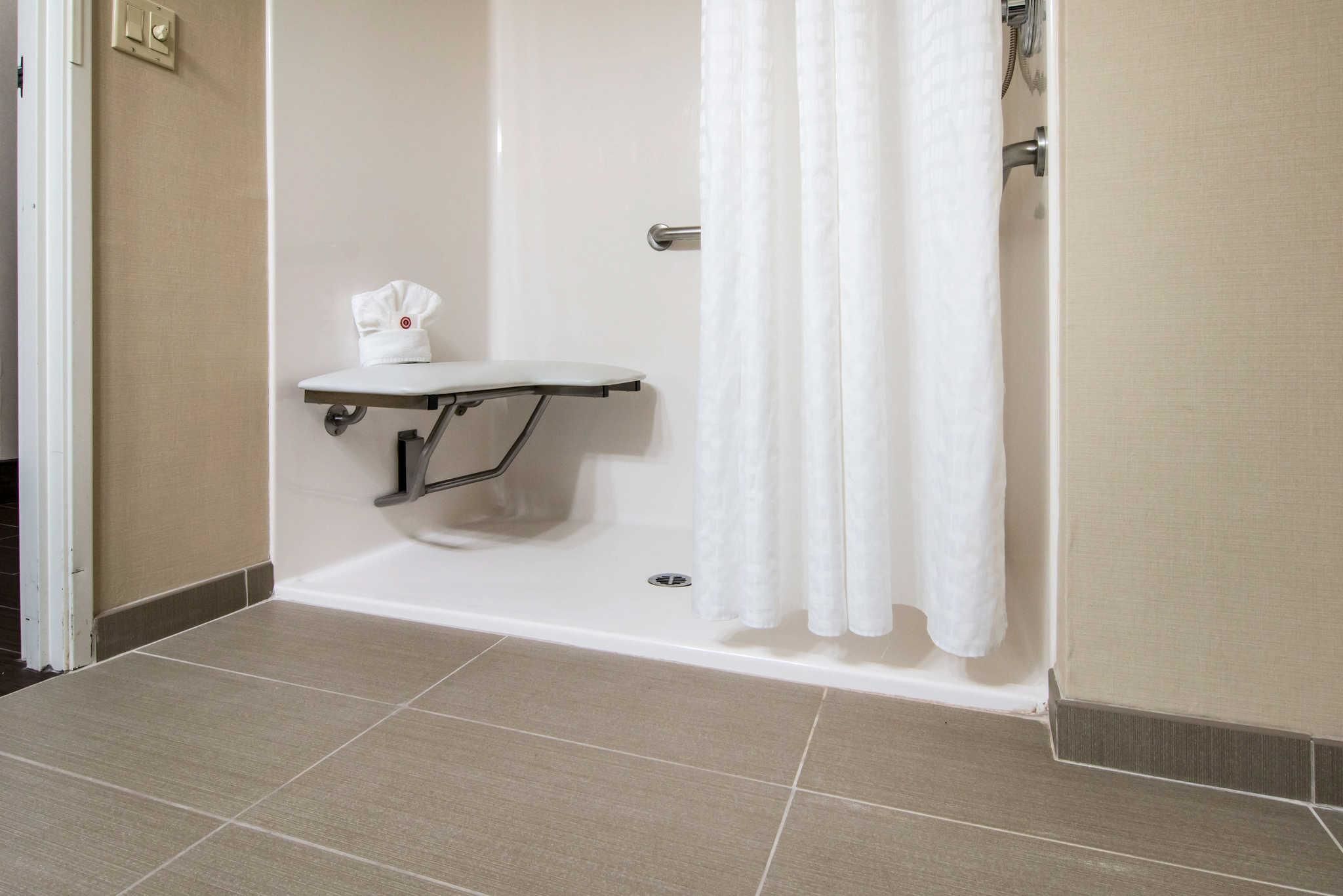 A shower area with a white towel rack, a white towel, and a shower curtain.