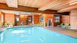 An indoor swimming pool with wooden walls and ceiling, surrounded by lounge chairs. - Comfort Suites Linn County (Albany)