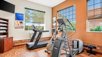 Un gimnasio con cintas de correr, elípticas y máquinas de pesas.