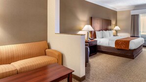 A hotel room with a bed, a sofa, a desk, and two lamps. - Comfort Suites Linn County (Albany)