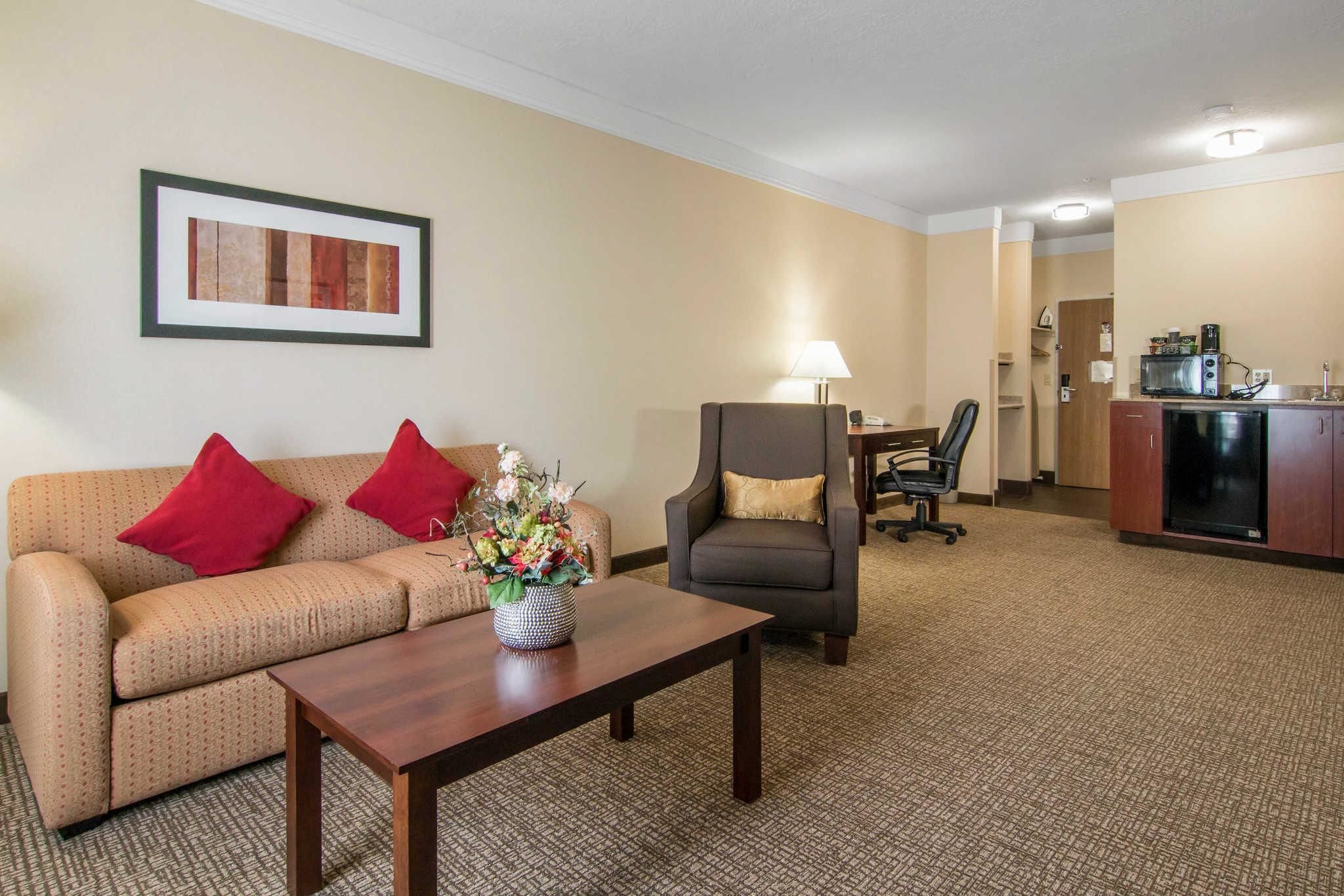 Habitación de hotel con sofá, sillón, mesa de centro y una zona de kitchenette.