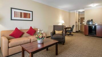 Habitación de hotel con sofá, sillón, mesa de centro y una zona de kitchenette.