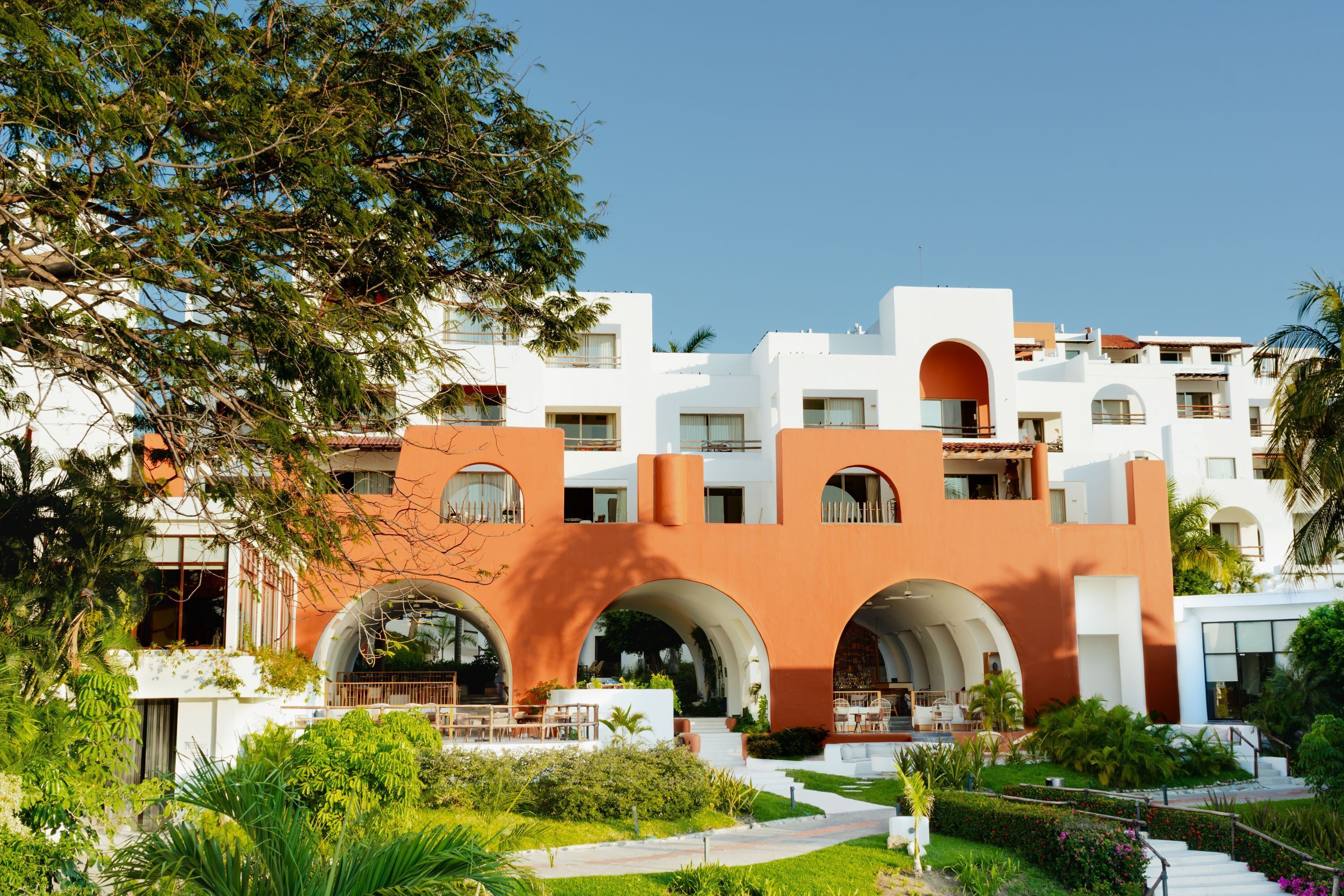 A hotel with a central courtyard, multiple balconies, and a mix of white and orange building facades.