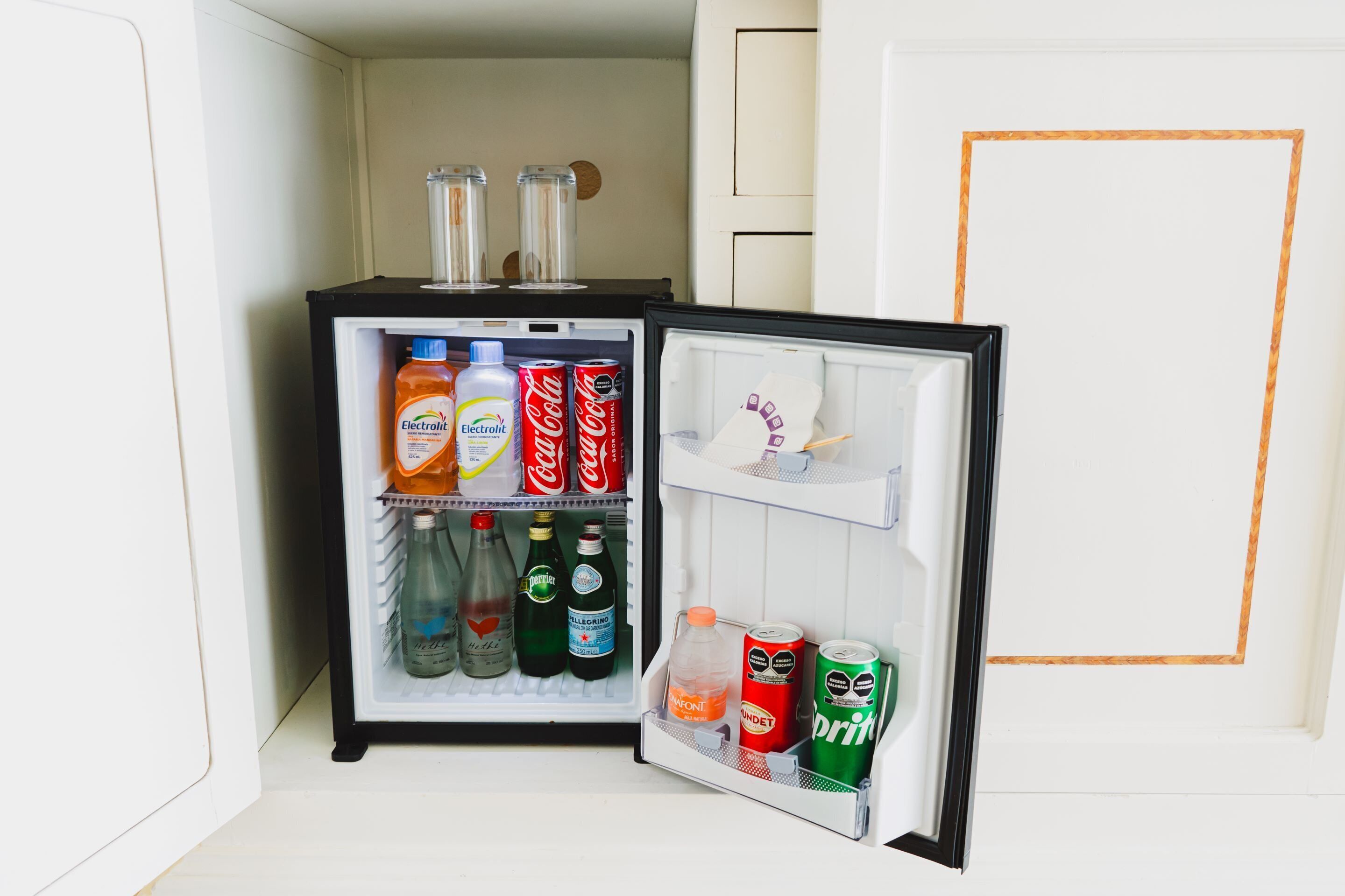 A mini-fridge with various beverages including sodas and water bottles.