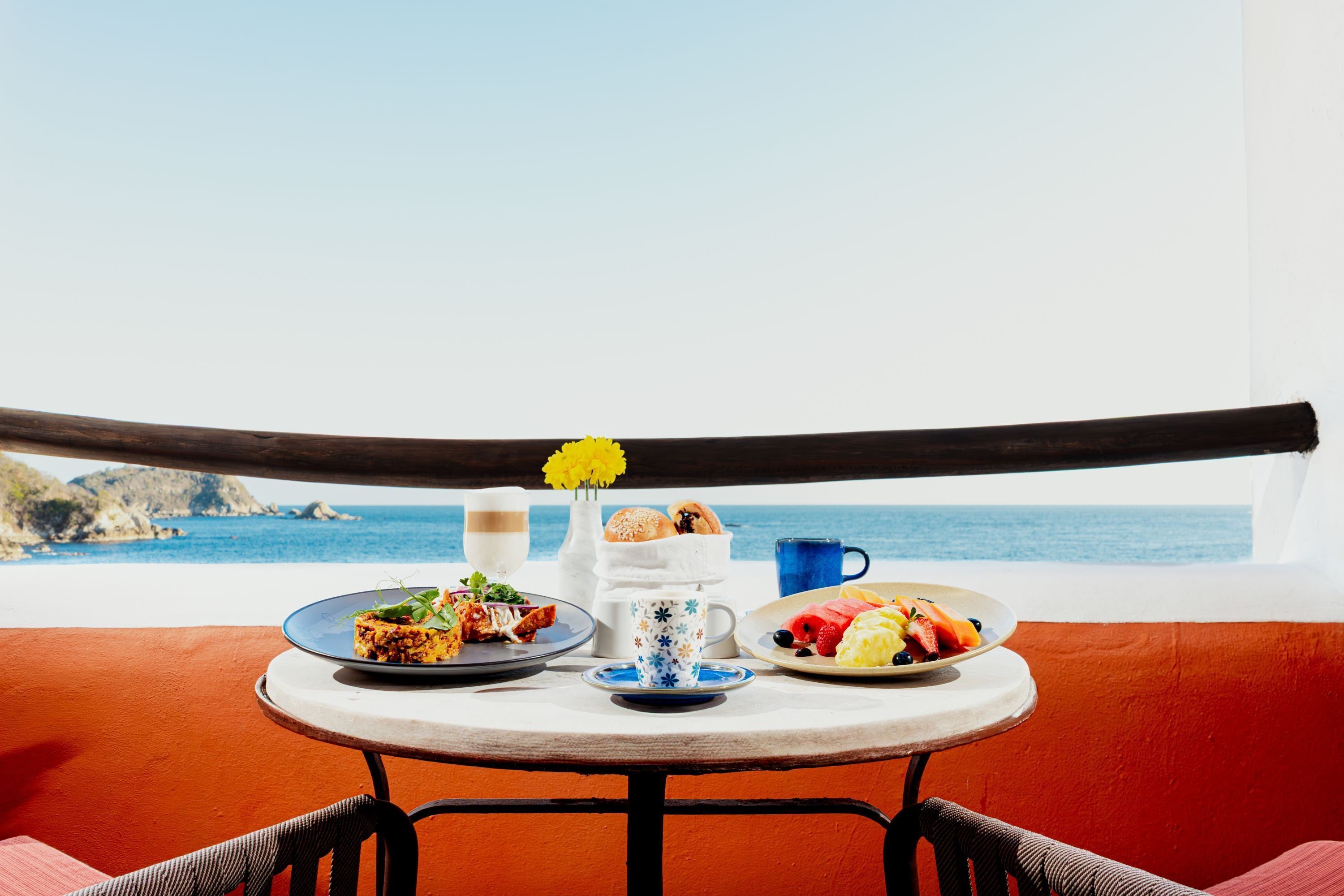 A table with breakfast items and a view of the ocean.