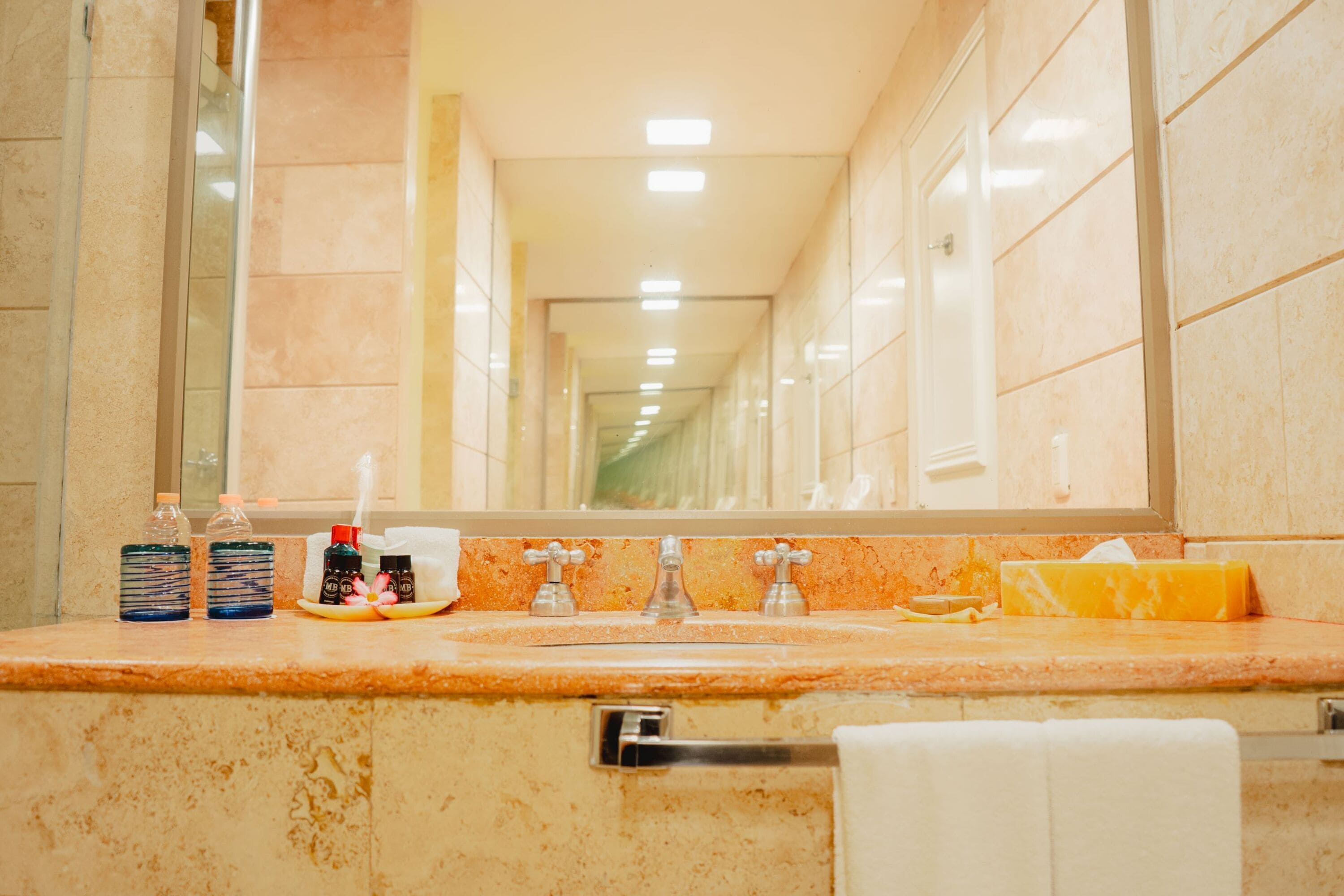 A bathroom with a marble countertop, a sink, a mirror, and toiletries.