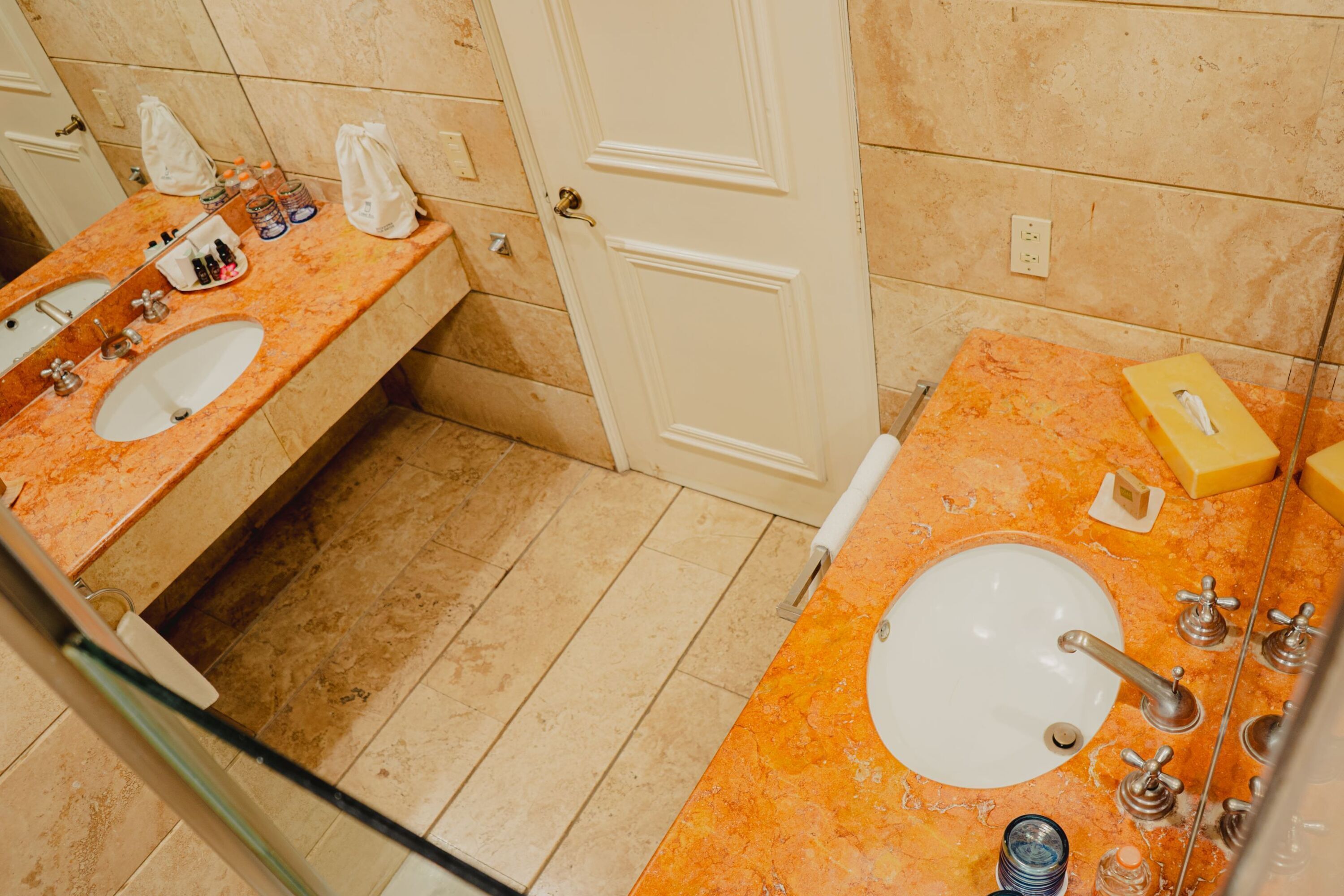 A bathroom with two sinks, marble countertops, and a door.