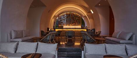 A spacious lounge area with a central staircase, sofas, and wicker chairs.