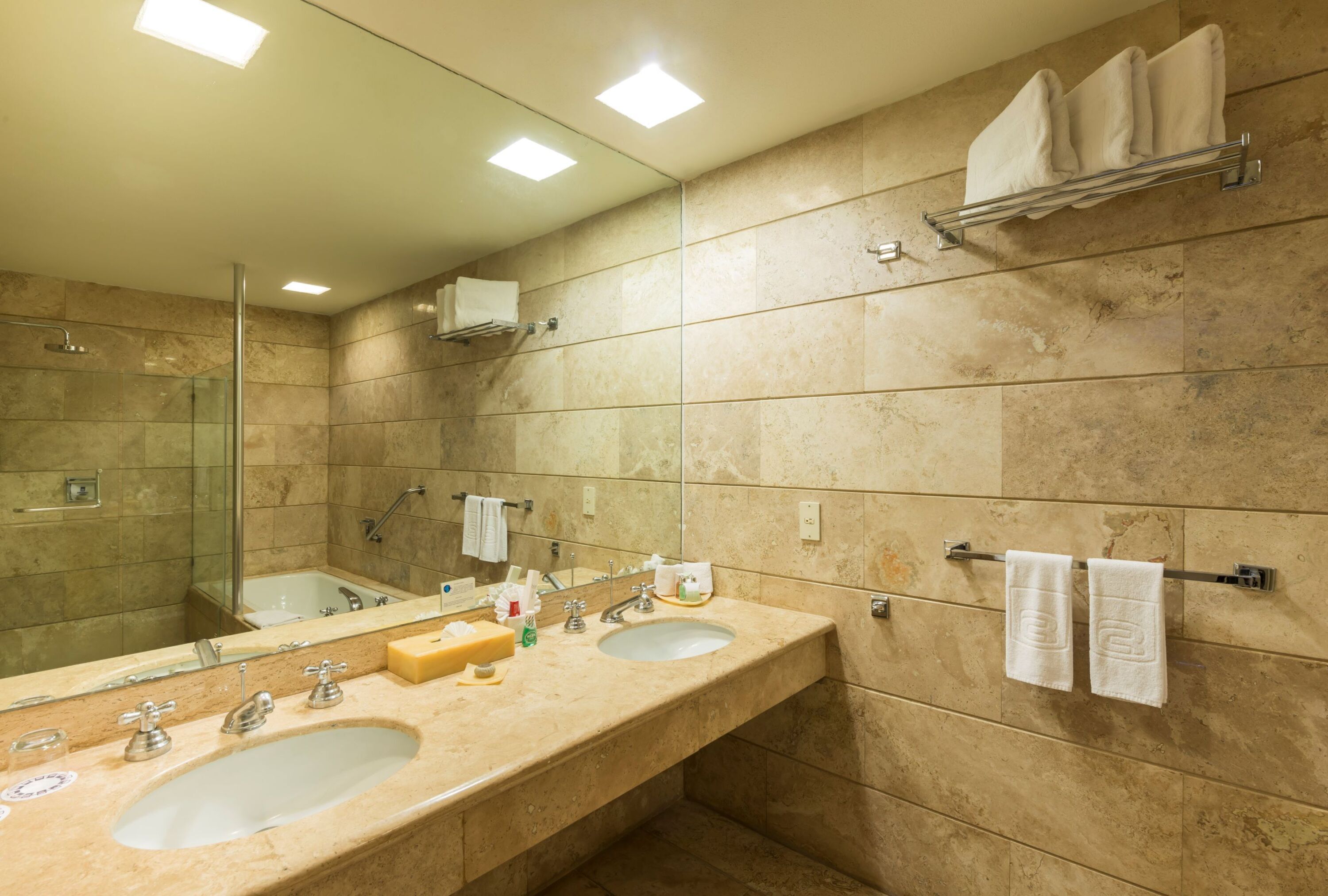 Un baño moderno con dos lavamanos, cabina de ducha de vidrio y un espejo grande.