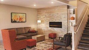 A modern living room with a sectional sofa, red armchairs, a coffee table, and a fireplace. - Country Inn & Suites by Radisson, Albert Lea - Austin (Albert Lea)