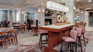 A hotel lobby with a bar area, seating arrangements, and a television. - Courtyard by Marriott Cranbury South Brunswick (Cranbury)