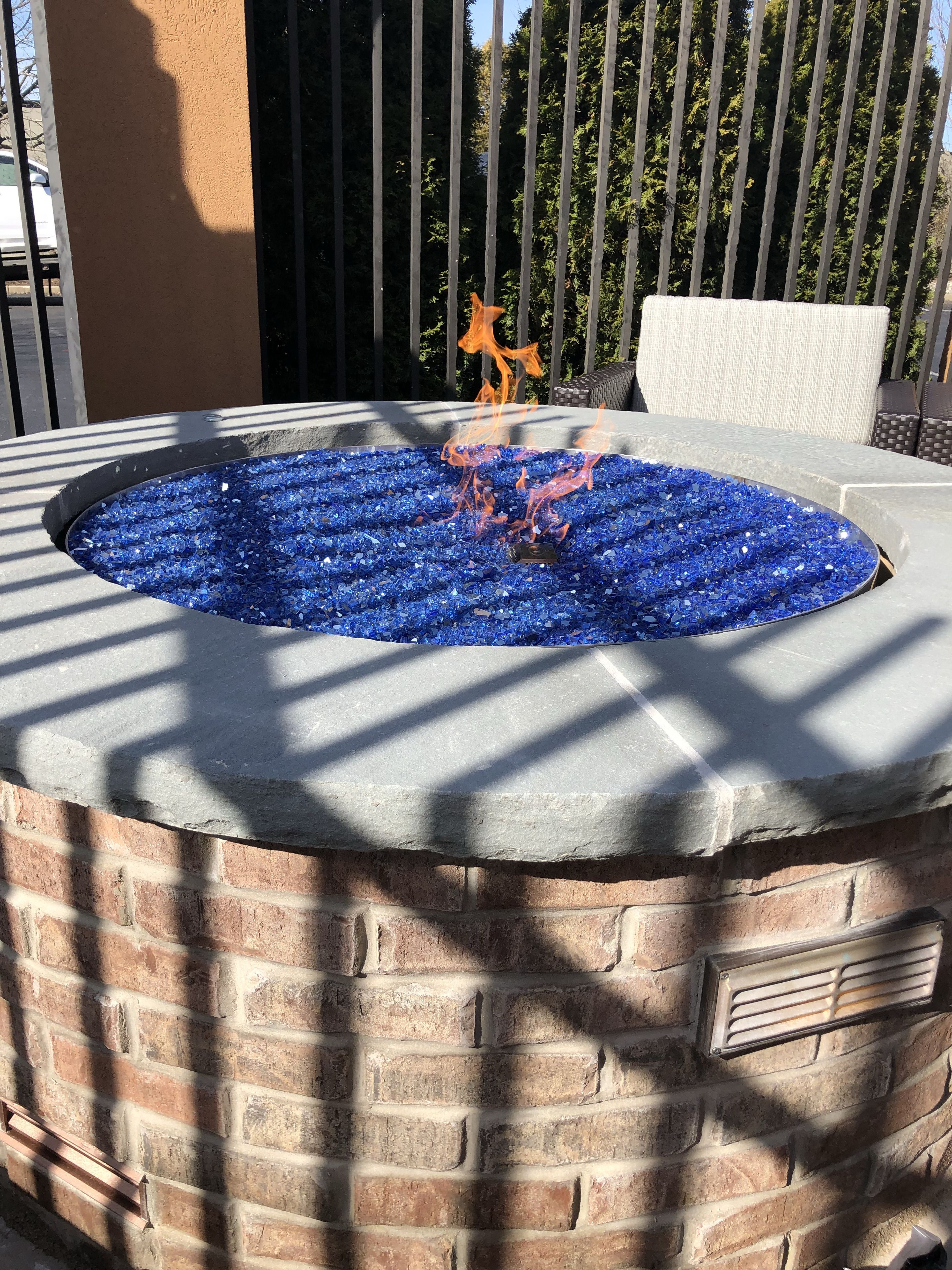 Una estructura circular al aire libre con piedras de vidrio azules y un brasero de metal.