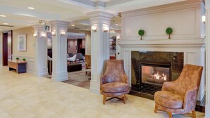 A spacious lobby with a fireplace, two leather armchairs, and a coffee table. - Courtyard by Marriott Cranbury South Brunswick (Cranbury)