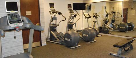 A gym with treadmills, elliptical machines, and a bench.