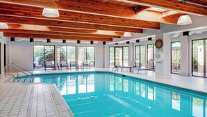 An indoor swimming pool with wooden beams, tiled floor, and large windows. - Courtyard by Marriott Cranbury South Brunswick (Cranbury)