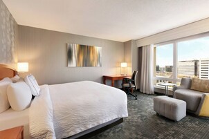 Una habitación de hotel con una cama grande, un escritorio, una silla y un sofá.