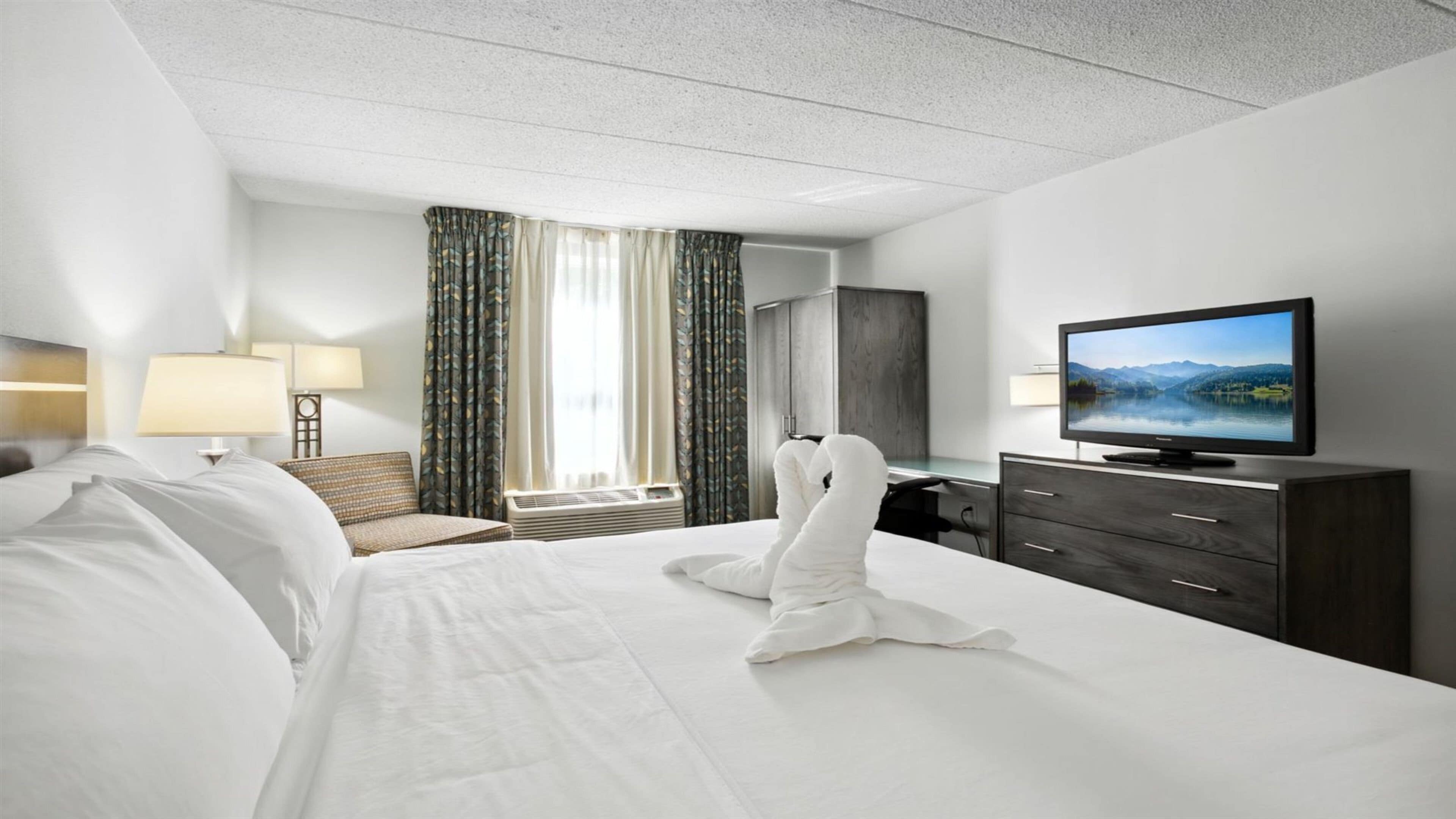 A hotel room with a bed, a television, a desk, and a wardrobe.