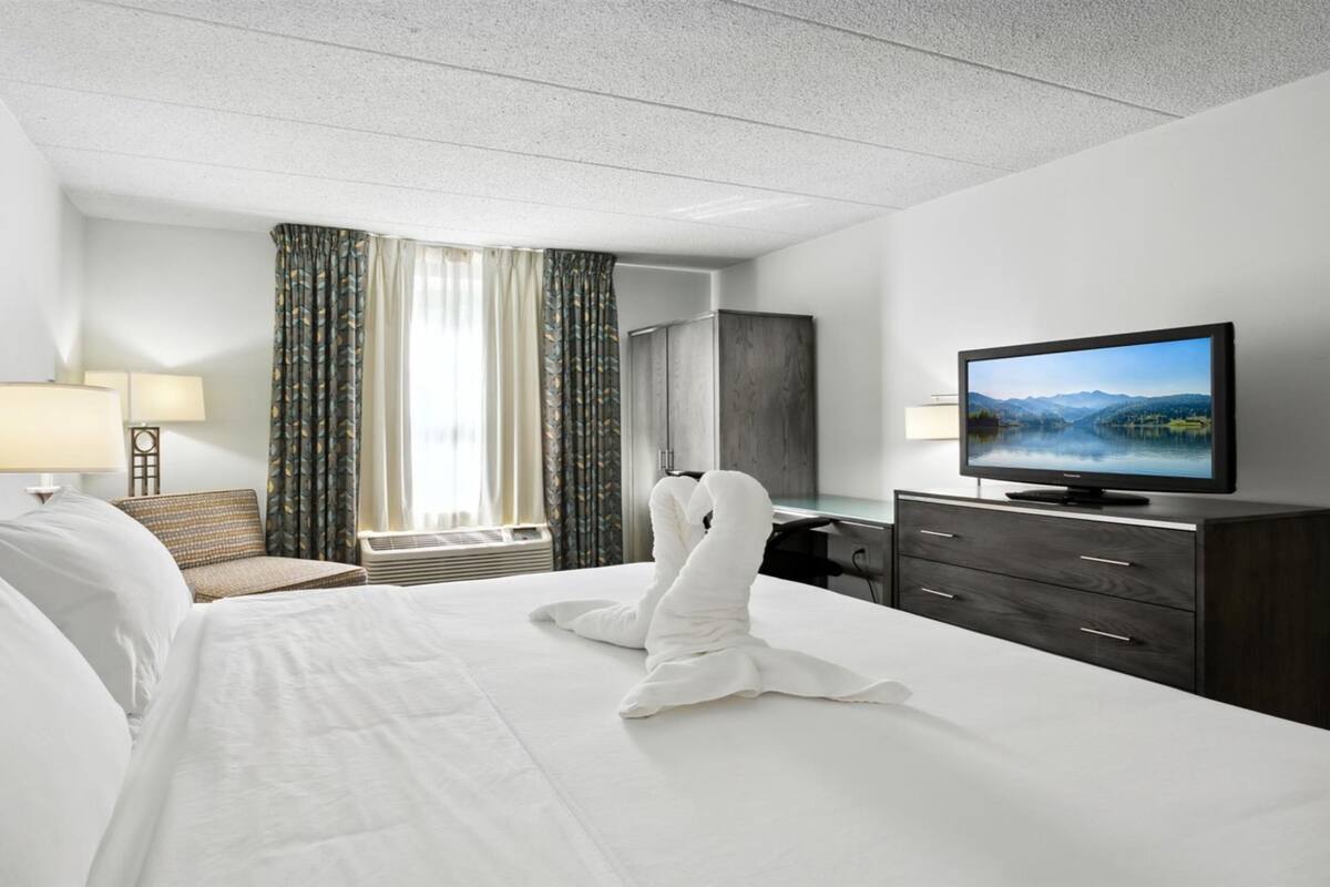 A hotel room with a bed, a television, a desk, and a wardrobe.