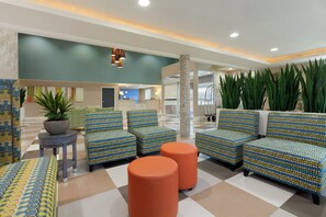 A lobby with patterned sofas, a coffee table, and a potted plant.