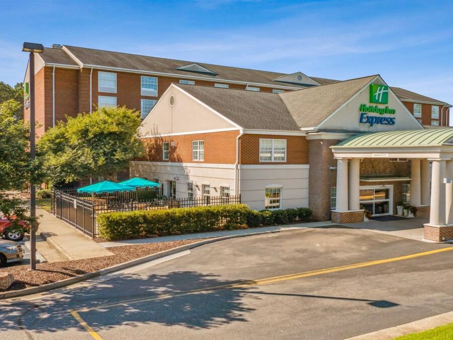Ein Holiday Inn Express Hotel mit überdachter Eingangspartie, Außenbereich mit Sitzgelegenheiten und einem Parkplatz.