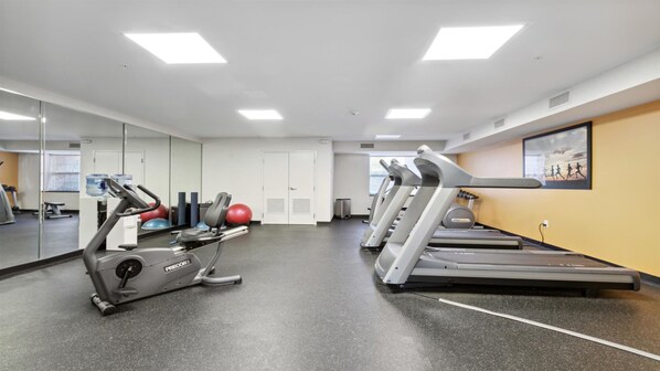 Un gimnasio con cintas de correr, elípticas y pelotas de ejercicio.
