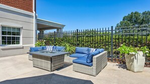 An outdoor patio with wicker furniture and a glass-top table. - Holiday Inn Express Williamsburg North by IHG (Williamsburg)
