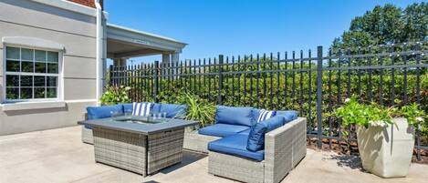 An outdoor patio with wicker furniture and a glass-top table.