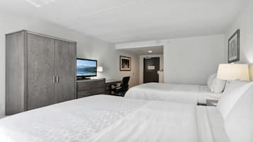 A hotel room with two beds, a desk, a television, and a wardrobe.