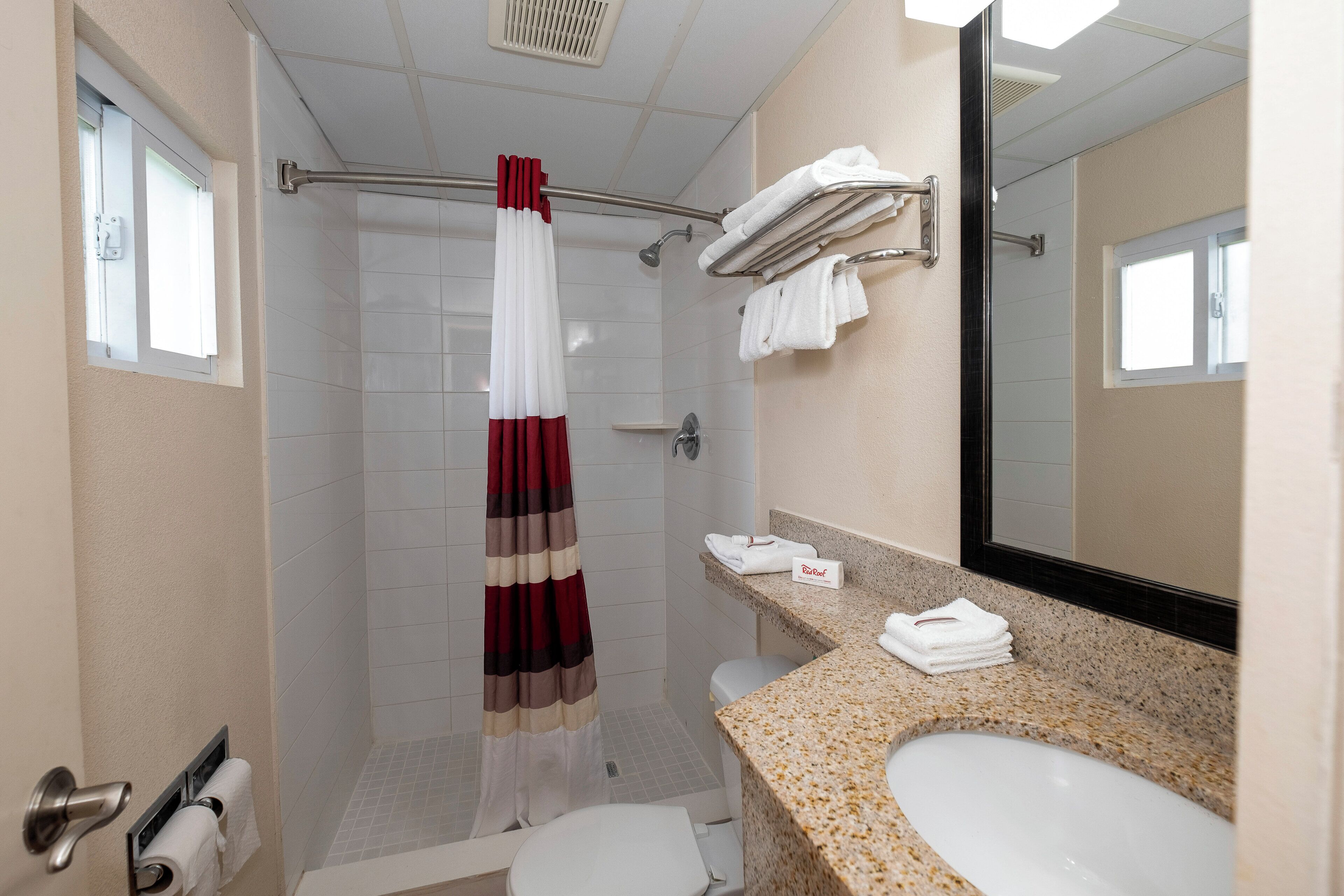 A bathroom with a shower, toilet, sink, and towel rack.