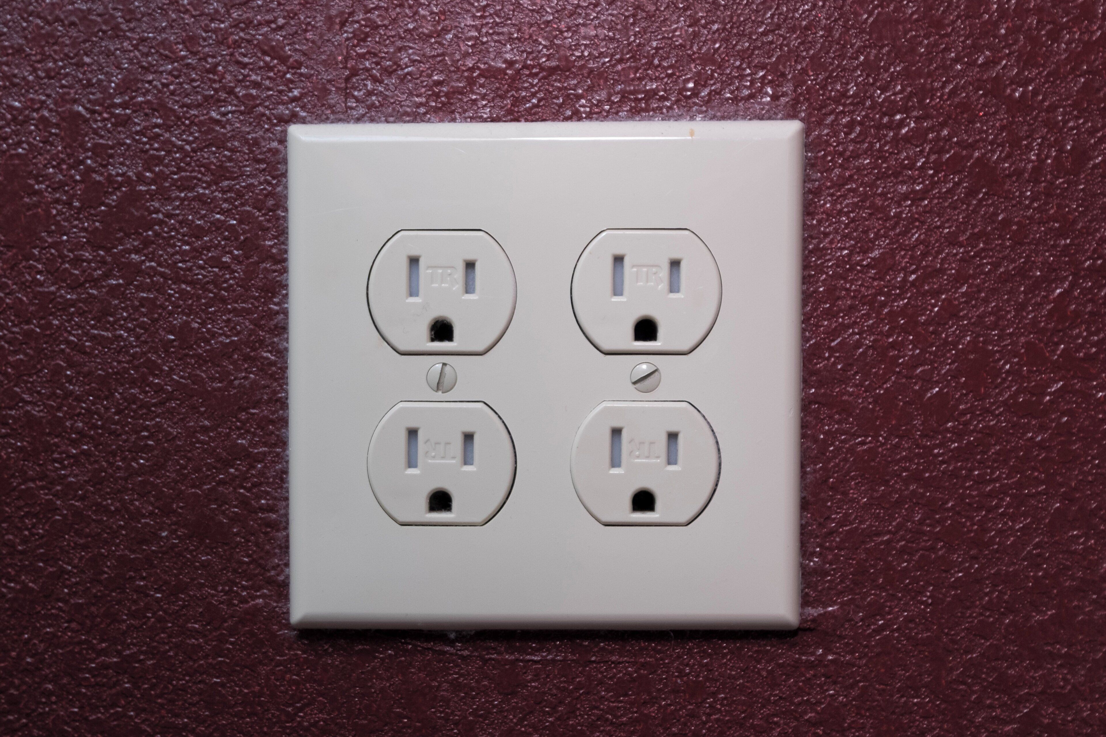 A four-socket electrical outlet on a textured wall.