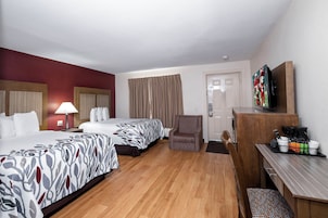 Una habitación de hotel con dos camas, un escritorio, una silla, un televisor y una cafetera.