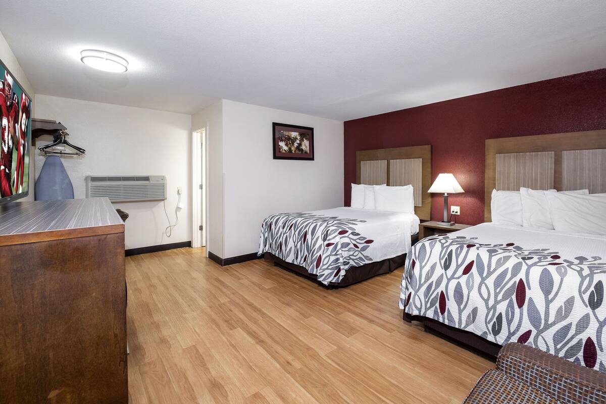 Ein Hotelzimmer mit zwei Betten, einem Schreibtisch und einem Kleiderschrank.