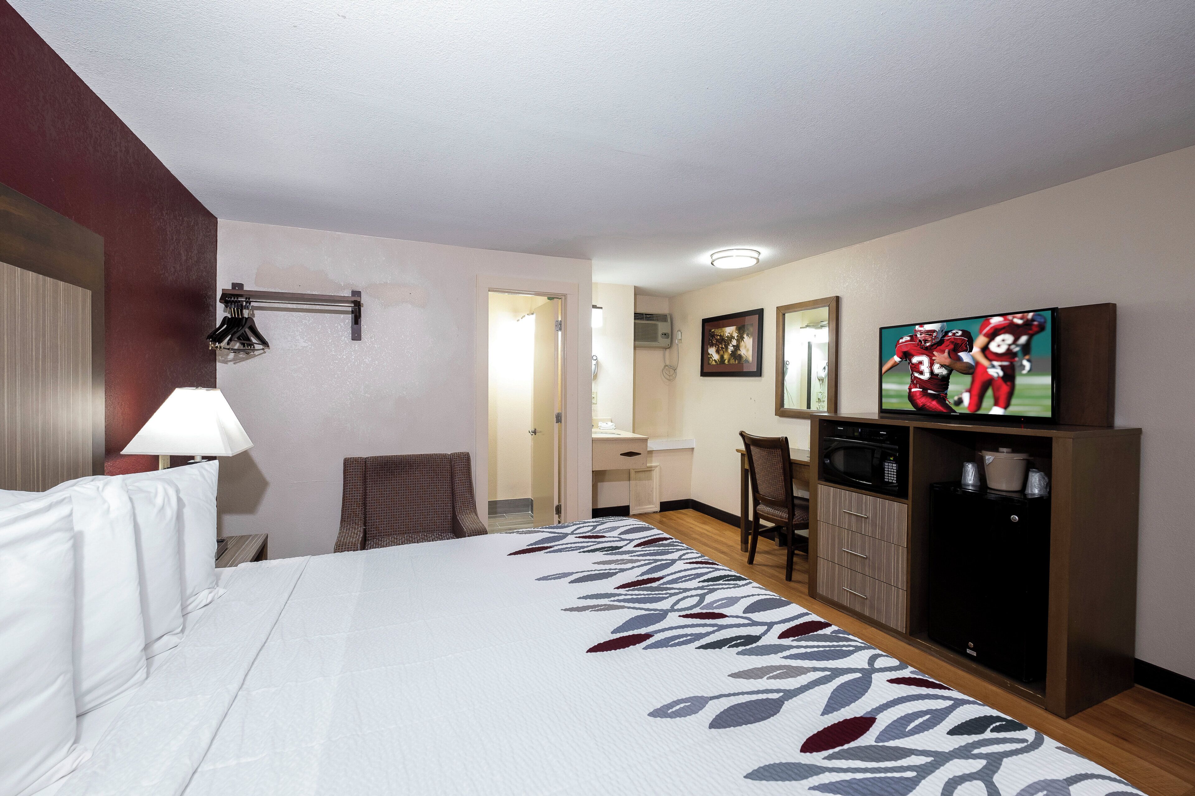 Ein Hotelzimmer mit Bett, Schreibtisch, Sessel, Fernseher und Mikrowelle.