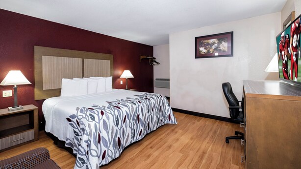 A hotel room with a bed, bedside lamps, a desk, and a chair. - Red Roof Inn Neptune - Jersey Shore (Neptune City)