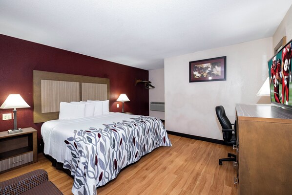 A hotel room with a bed, bedside lamps, a desk, and a chair.
