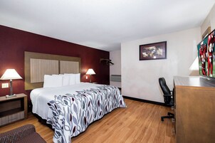 Una habitación de hotel con cama, lámparas de noche, un escritorio y una silla.