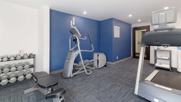 A fitness center with treadmills, an elliptical, and dumbbells.