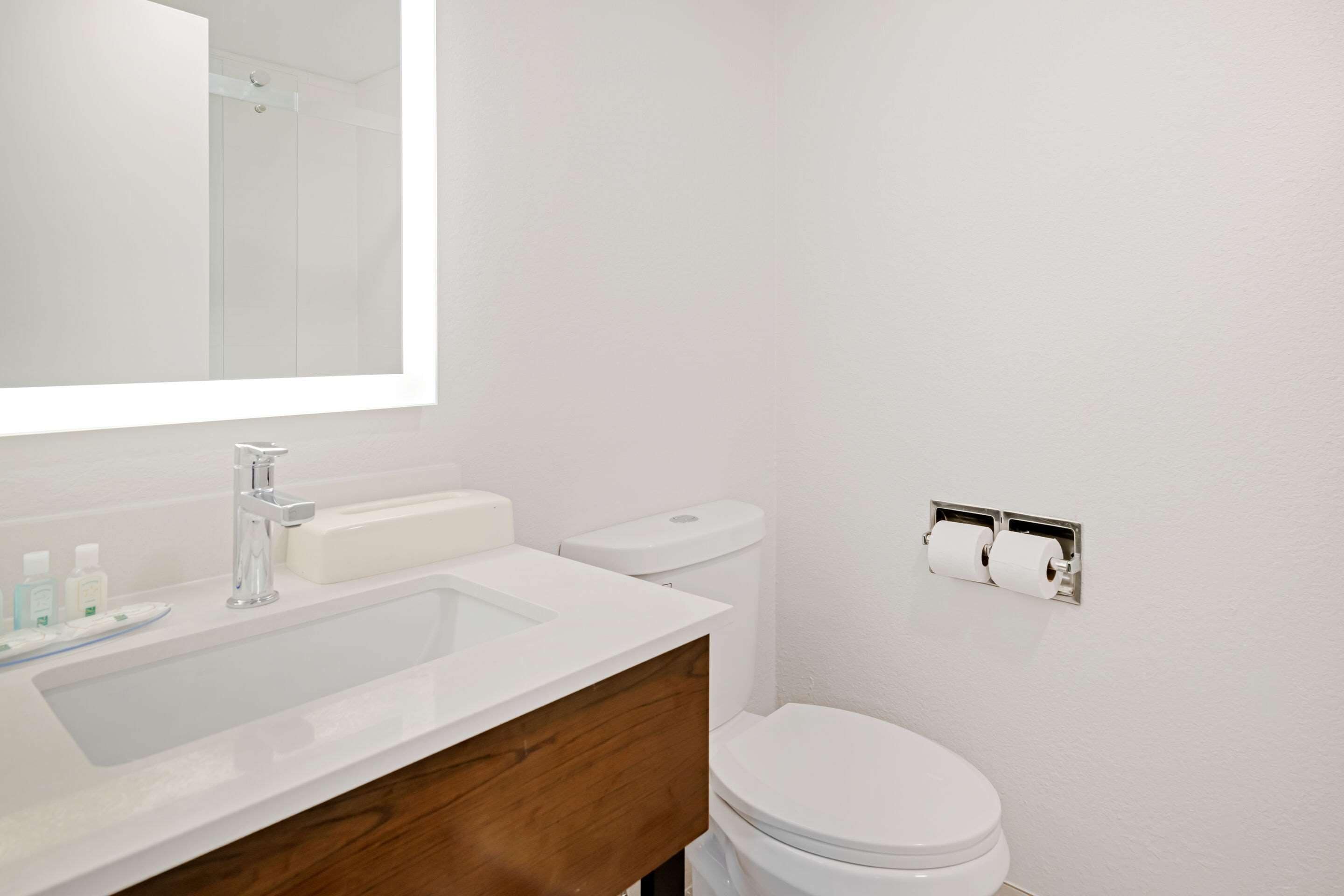 A bathroom with a white sink, mirror, and toilet.