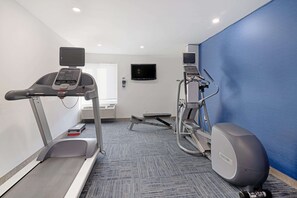 A fitness room with a treadmill, elliptical, and stationary bike.